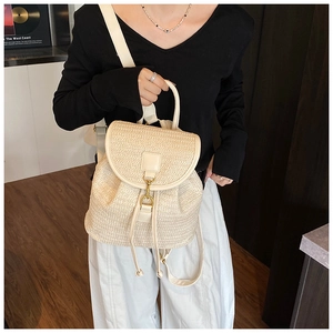 Dettaglio dello zaino in paglia intrecciata beige con chiusura a coulisse e manico in pelle