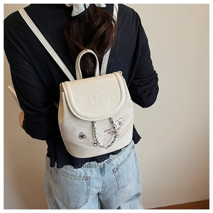Detail of white leather mini backpack with chain strap and embossed lettering on model
