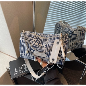 Detail of blue and white patterned cylindrical crossbody bag with pearls and silver chains