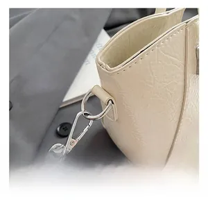 Detailed close-up of silver metal hook and pleated texture on cream bucket bag