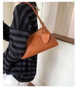 Detailed close-up of brown woven shoulder bag featuring hand-knotted strap and leather charms