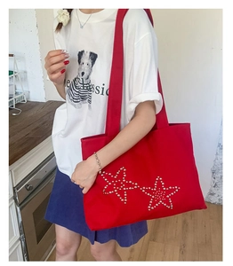 Red canvas tote bag with sparkling star rivets shown on model in lifestyle setting