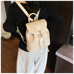 Dettaglio dello zaino in paglia intrecciata beige con spallacci in pelle e fibbia