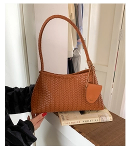 Detailed close-up of the high-density brown leather woven texture on a shoulder bag