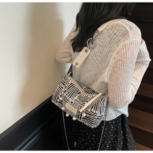 Detail of zebra pattern crossbody bag with silver chains, pearls and wide branded strap