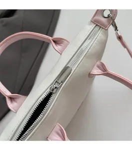 Détail de la fermeture éclair métallique et de la poignée rose sur le sac seau blanc