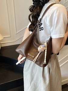 Brown litchi grain hobo shoulder bag with metal logo and plush monkey charm on model