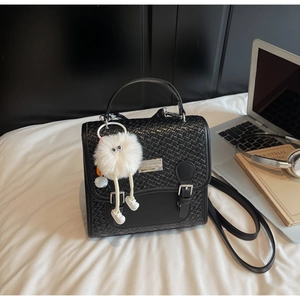 Détail du sac à dos vintage noir avec texture tressée et charmant pendentif peluche