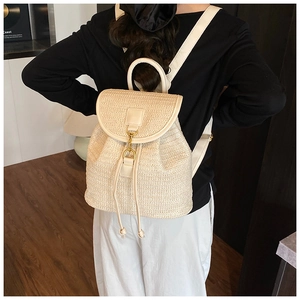 Detail of woven straw backpack showing beige texture, drawstring, and gold hook closure