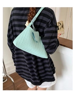 Detail of mint green woven underarm bag featuring a unique spiral knot handle design