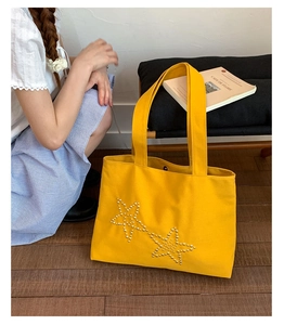 Detailed view of yellow canvas tote bag with star rivets and casual twin handles