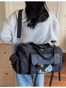 Large black canvas travel duffel bag with stylish patches and adjustable shoulder strap