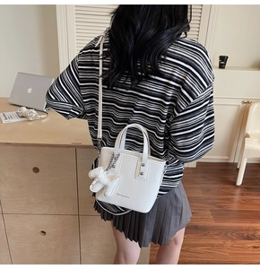 Vue détaillée du sac seau blanc en cuir PU texturé avec un joli pendentif d'ours blanc