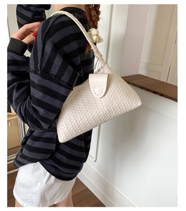 Close-up of cream woven shoulder bag featuring intricate texture and thin strap detail