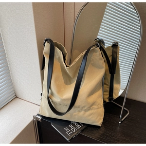 Detail of khaki canvas bucket bag with black leather straps and metal side buckle