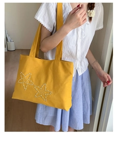 Detail of a bright yellow canvas tote bag with handcrafted pearl star embroidery