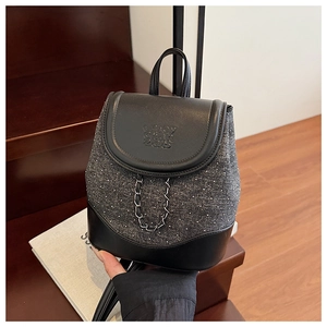 Detail of mini backpack featuring polka dot denim, PU leather textures, and metal chain