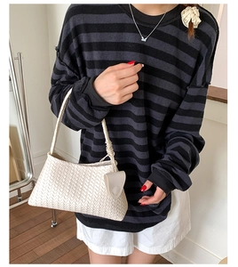 Detailed view of cream woven crescent bag with textured leather pattern and round charm