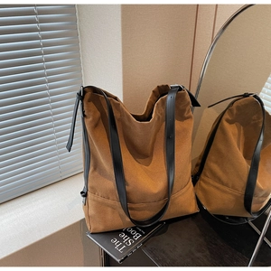 Detail of large brown canvas tote bag with black strap and adjustable metal buckle