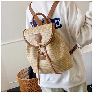 Dettaglio zaino in paglia intrecciata con patta in pelle e fibbia a gancio in metallo