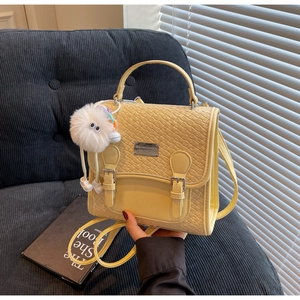 Détail du sac à dos en cuir tressé jaune avec poignée et charmant pompon blanc