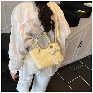 Detail view of yellow bucket bag with ruffled texture and heart pearl bow charm