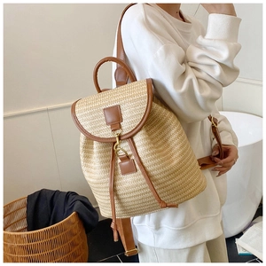 Detail of woven straw backpack featuring brown leather trim and metal hook closure