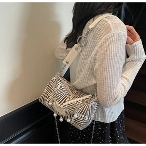 Detail of canvas cylinder bag featuring retro geometric patterns and pearl chain accents