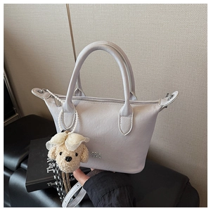 Vue détaillée d'un sac seau gris clair élégant avec anses et pendentif en peluche mignon