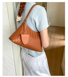 Close-up of woven brown leather shoulder bag with intricate Intrecciato craftsmanship