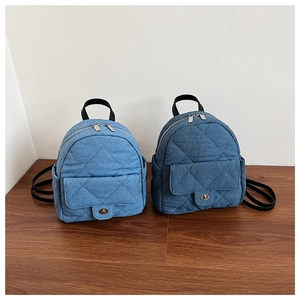 Detail view of mini quilted denim backpacks in light and dark blue with metal twist locks