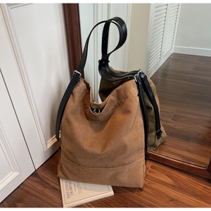 Detail of brown canvas bucket bag with black leather strap and metal buckle adjustment