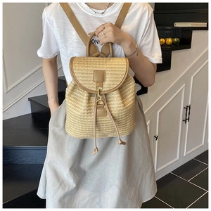 Dettaglio dello zaino in paglia intrecciata con trama beige e finiture in pelle marrone