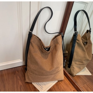 Detail view of large brown canvas tote bag with black leather strap and metal buckle