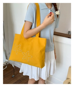 Detail of yellow canvas tote bag with silver studs star pattern for casual summer outfits