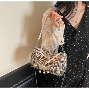 Detail of striped barrel bag featuring pearl chain strap and silver metal hardware
