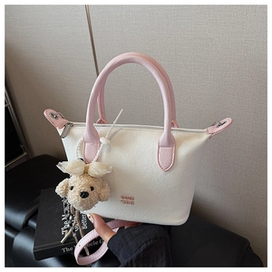 Détail du sac seau en cuir blanc et rose avec breloque chien en peluche et bandoulière