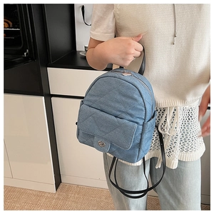 Detail of blue denim quilted backpack with silver metallic twist lock and black leather straps