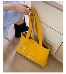 Macro detail of yellow canvas tote bag with pearl star rivets and large capacity