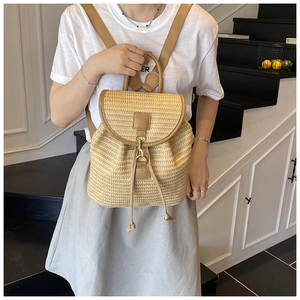 Detail of woven straw backpack with brown leather trim and metal buckle closure