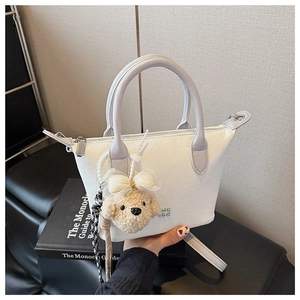 Détail du sac seau en cuir crème avec bordure violette et breloque ours en peluche
