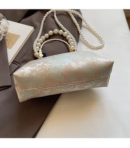 Detail of vintage jacquard crossbody bag with pearl chain strap and gold circular handle