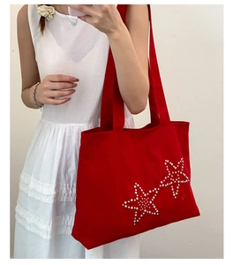 Mirror selfie showing a red canvas tote bag with stylish studded star details on the side