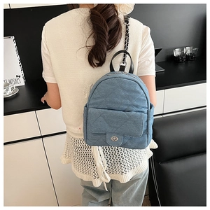 Close-up of quilted denim mini backpack with twist-lock and metal chain detail