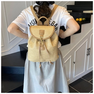 Close-up of straw backpack with leather straps and gold buckle worn by a model