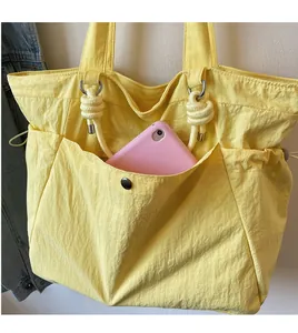 Close-up of yellow nylon tote bag featuring front pocket and decorative knot detail
