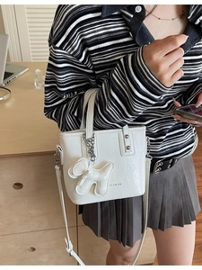 Sac seau blanc avec clous argentés et pendentif animal porté par un mannequin