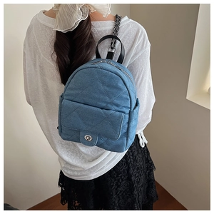 Detail of blue denim quilted mini backpack with chain strap on a model back