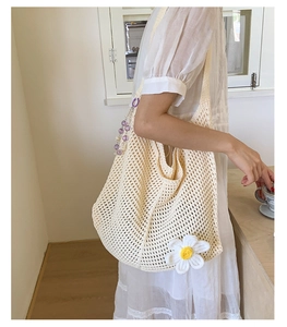 Detail der cremefarbenen Häkeltasche mit Gänseblümchen-Dekor und lila Perlenkette
