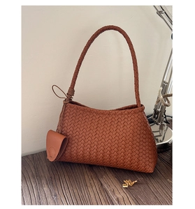 Detail of a brown woven shoulder bag featuring a matching mini round coin purse charm